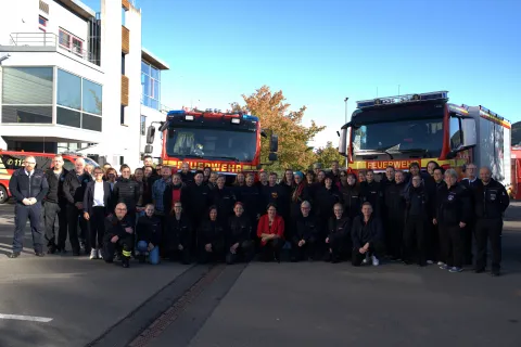 Gruppe von Feuerwehrmenschen in Uniform vor zwei Feuerwehrautos